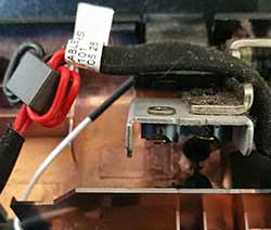 Une fixation de charnière a endommagée le câble d'alimentation de ce PC portable.